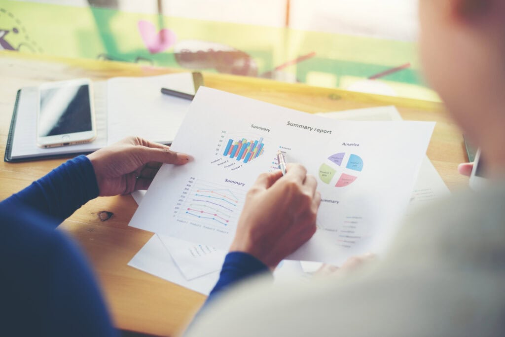 Business woman holding business graph information and pointing at it with a pen