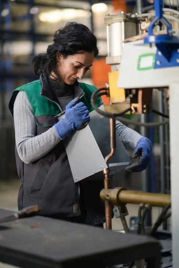 A woman working in a modern metal factory assembles parts for a new machine