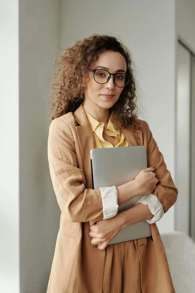 Automatization professional standing in office, holding closed laptop
