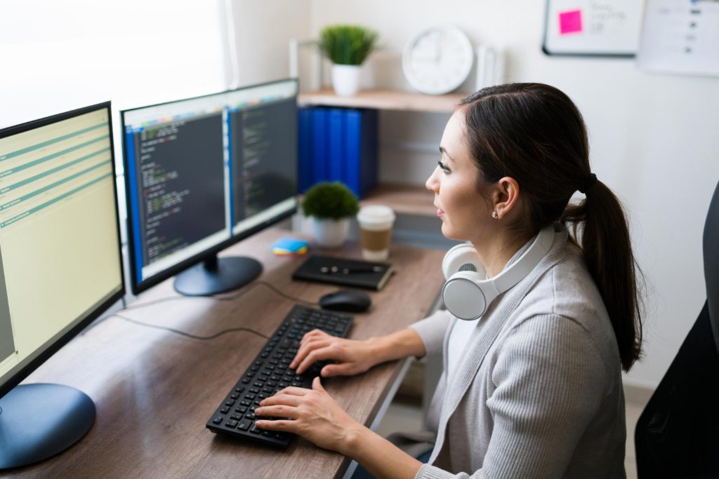 Female IT integration services expert coding at her desk in a office, using